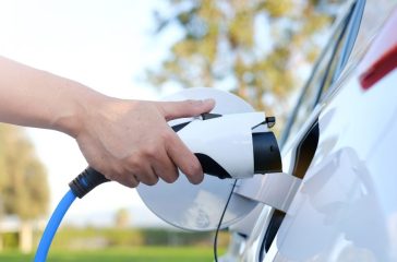 Electric car or ev is charging at station . man use the white po